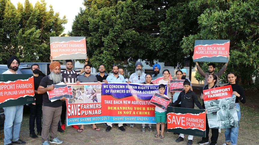 People stand with placards reading 'support farmers, save Punjab, save India'