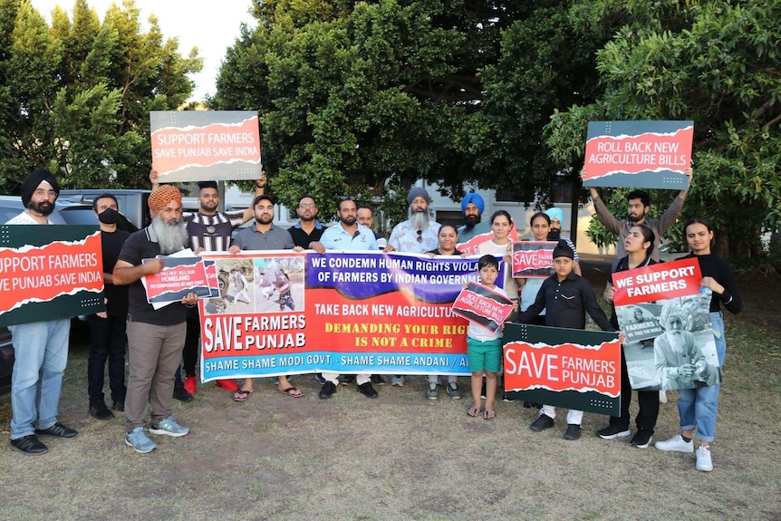 People stand with placards reading 'support farmers, save Punjab, save India'