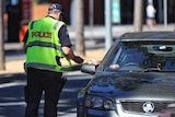 A Queensland police officer checks the ID of a motorist in Grey Street at South Brisbane.