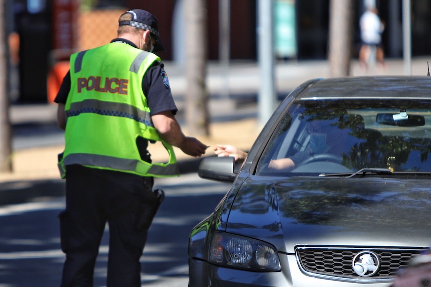 A Queensland police officer checks the ID of a motorist in Grey Street at South Brisbane.