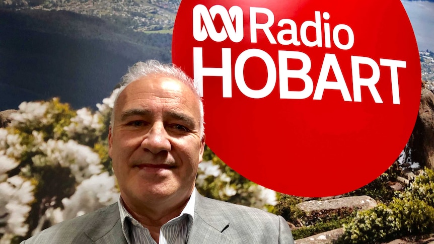 Robert Pradolin, Property Developer, Founder and Director of Housing All Australians standing in front of ABC Radio Hobart sign