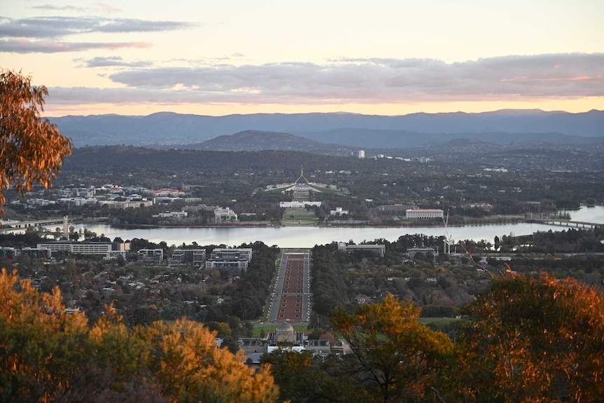 A orange and pink glow covers Canberra's landmarks from Mount Ainslie.