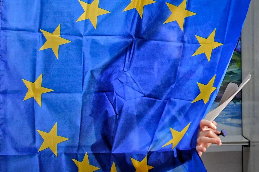 A woman is seen exiting a voting cabin in Romania.