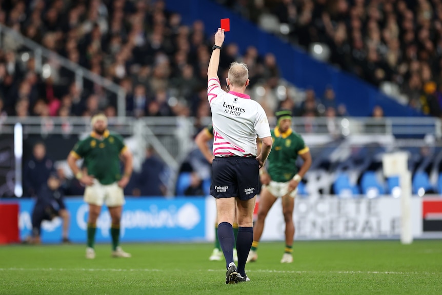 Referee Wayne Barnes holds up a red card for All Blacks captain Sam Cane during the Rugby World Cup final.