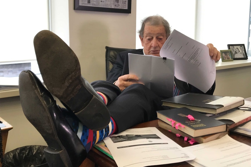 Brian Bourke reads papers in his office with his feet on the desk.