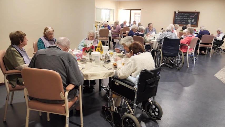 Four tables of older people having meals together.