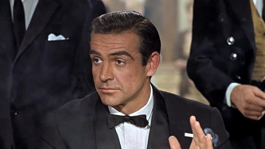 A man in a tuxedo and holding a cigarette