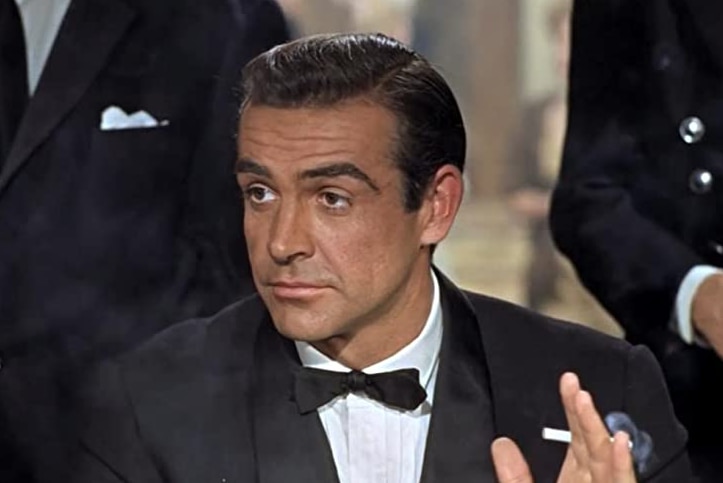 A man in a tuxedo and holding a cigarette