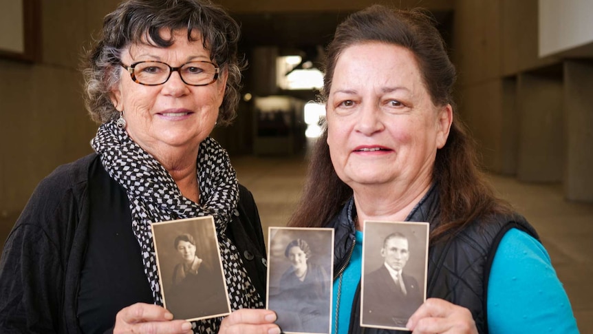 Two ladies holding black and white photos.