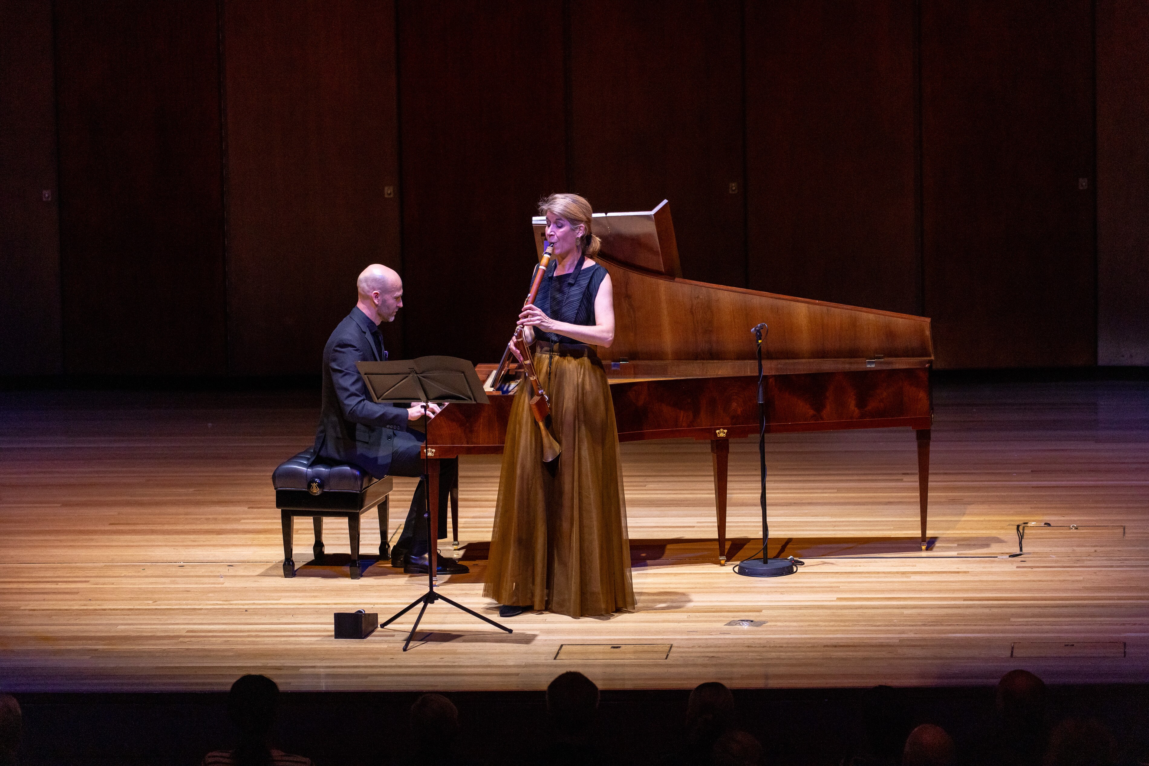 The clarinetist Nicola Boud performing with Erin Helyard at the fortepiano on a wood-paneled stage in front of an audience.