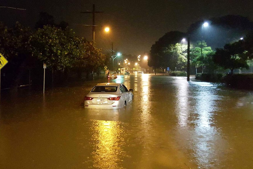 A car in water halfway up its wheels on a flooded street in Kirra on the Gold Coast on Saturday night