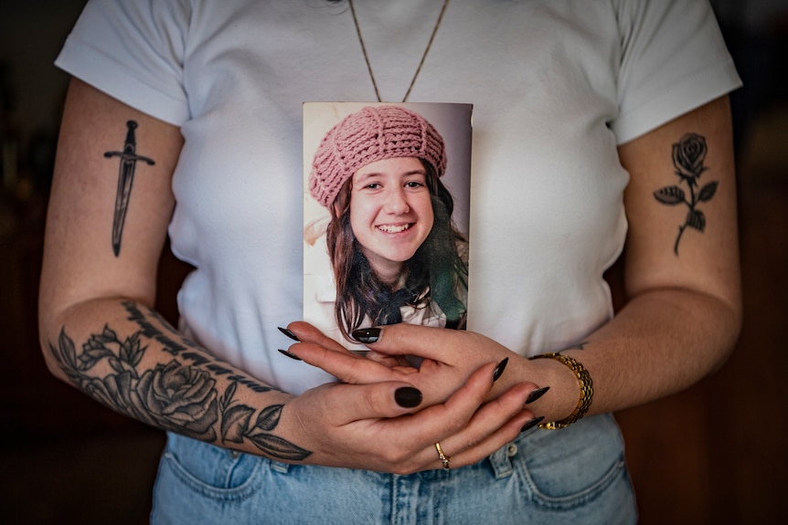 A woman holding a photo of a young girl.