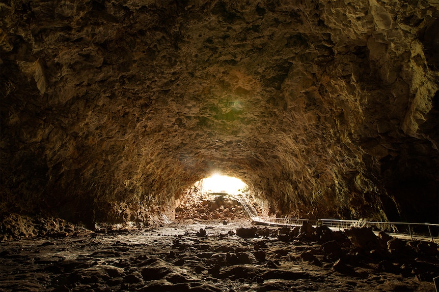 A large underground tunnel with bright sunshine at the end