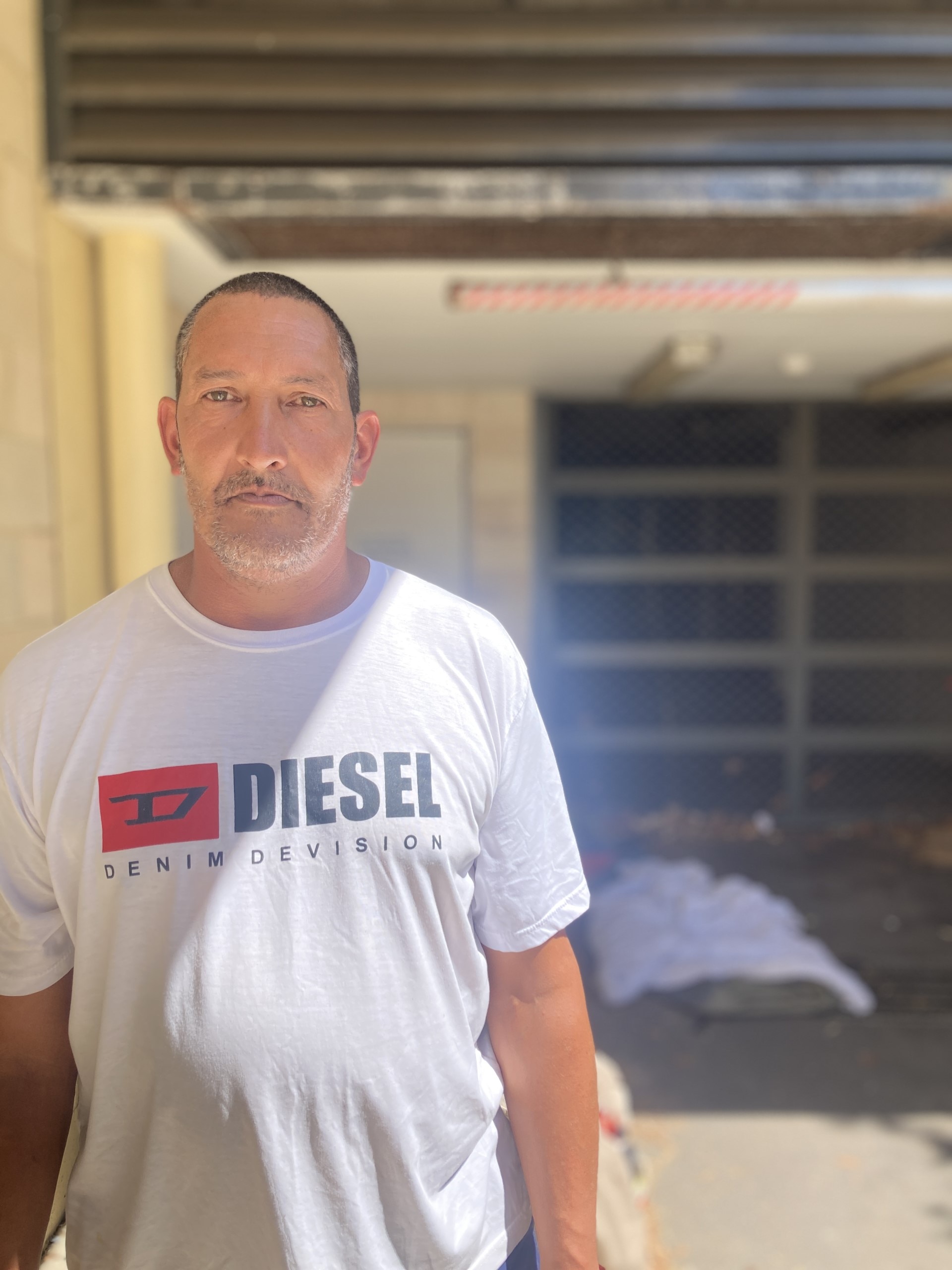 Man standing with belongings outside building