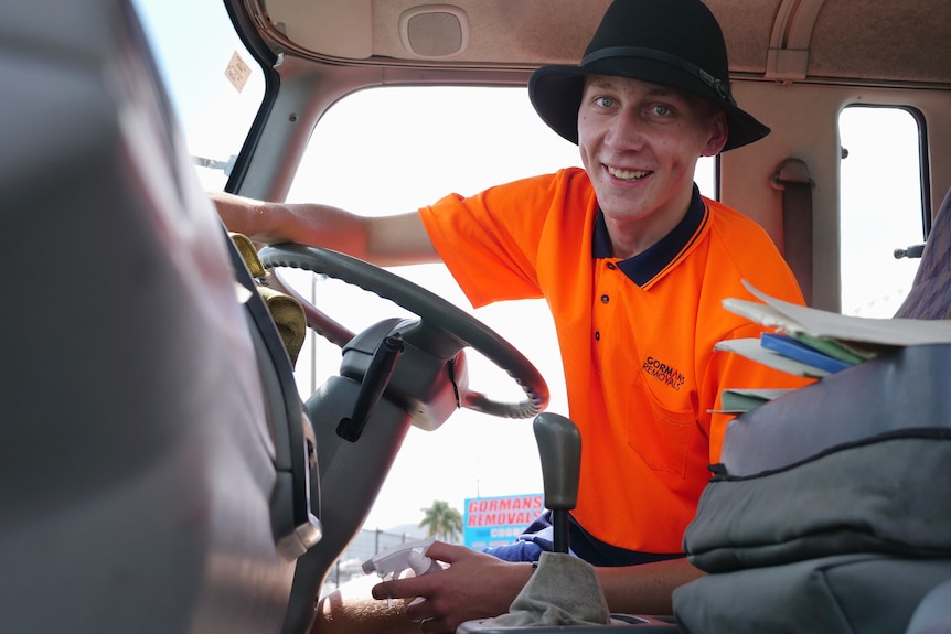 Nathan in the front of a truck, sitting in the drivers seat, steering wheel in front, wiping the dashboard. Ausnew Home Care, NDIS registered provider, My Aged Care