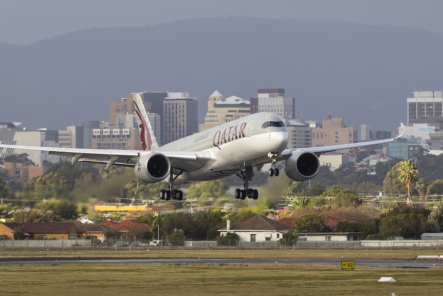 plan landing on tarmac with wheel down and cityscape in the background