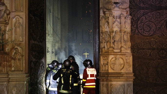 Paris Fire brigade members are seen at an entrance that looks into the Notre Dame Cathedral.