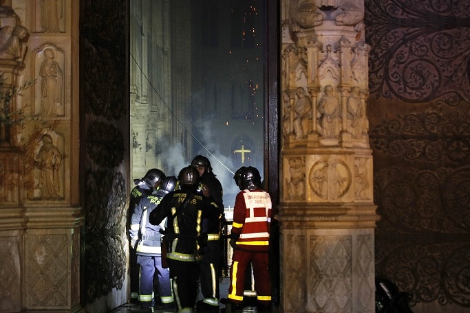 Paris Fire brigade members are seen at an entrance that looks into the Notre Dame Cathedral.