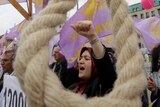 A woman protests behind a noose hanging in the street.