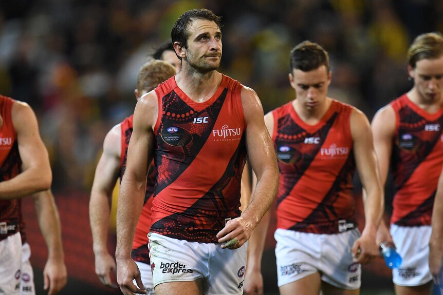 Jobe Watson of Essendon walks off the ground with teammates after a game against Richmond