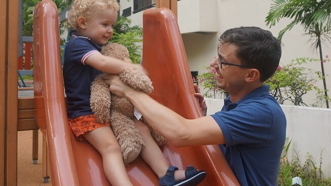Stephen Dziedzic and his son play on a slide in Singapore.