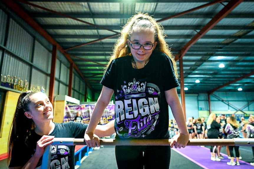 A girl hangs on a bar and smiles at the camera.