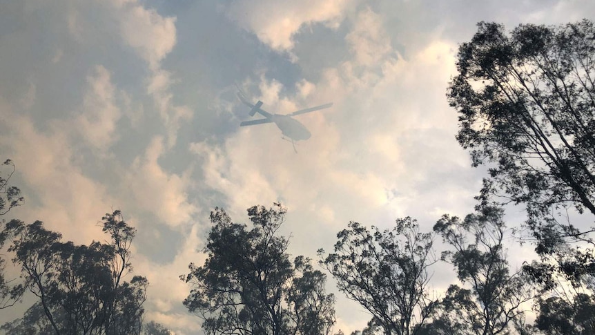 Smoke shadows helicopter waterbombing bushfire at Laidley