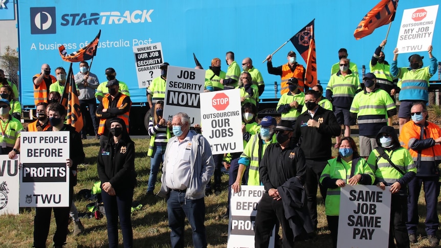 Workers waving flags and holding placards at a strike protest at StarTrack.
