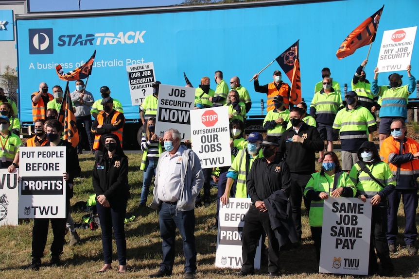 Workers waving flags and holding placards at a strike protest at StarTrack.