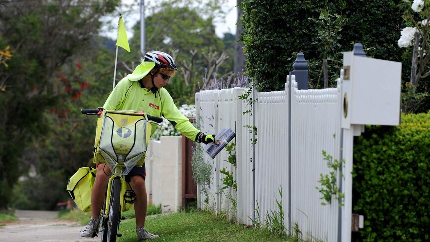 An Australia Post worker delivers mail by pushbike in suburban Sydney.