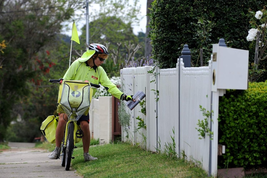 An Australia Post worker delivers mail by pushbike in suburban Sydney.