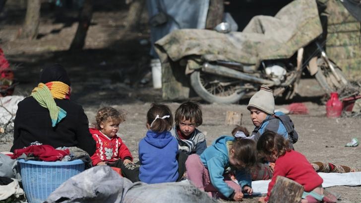 Several children pictured sitting in the middle of a refugee camp in Syria.