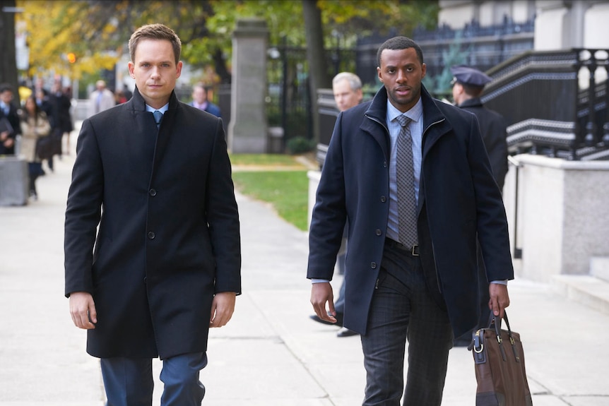 Two men in suits walking on the street outside a court.