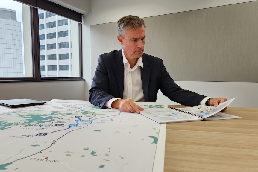 A man sits at a table, he is looking at maps of new south wales