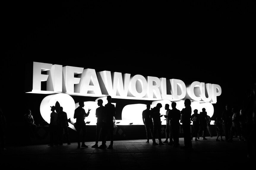 Un panneau blanc qui lit FIFA WORLD CUP est visible derrière les gens