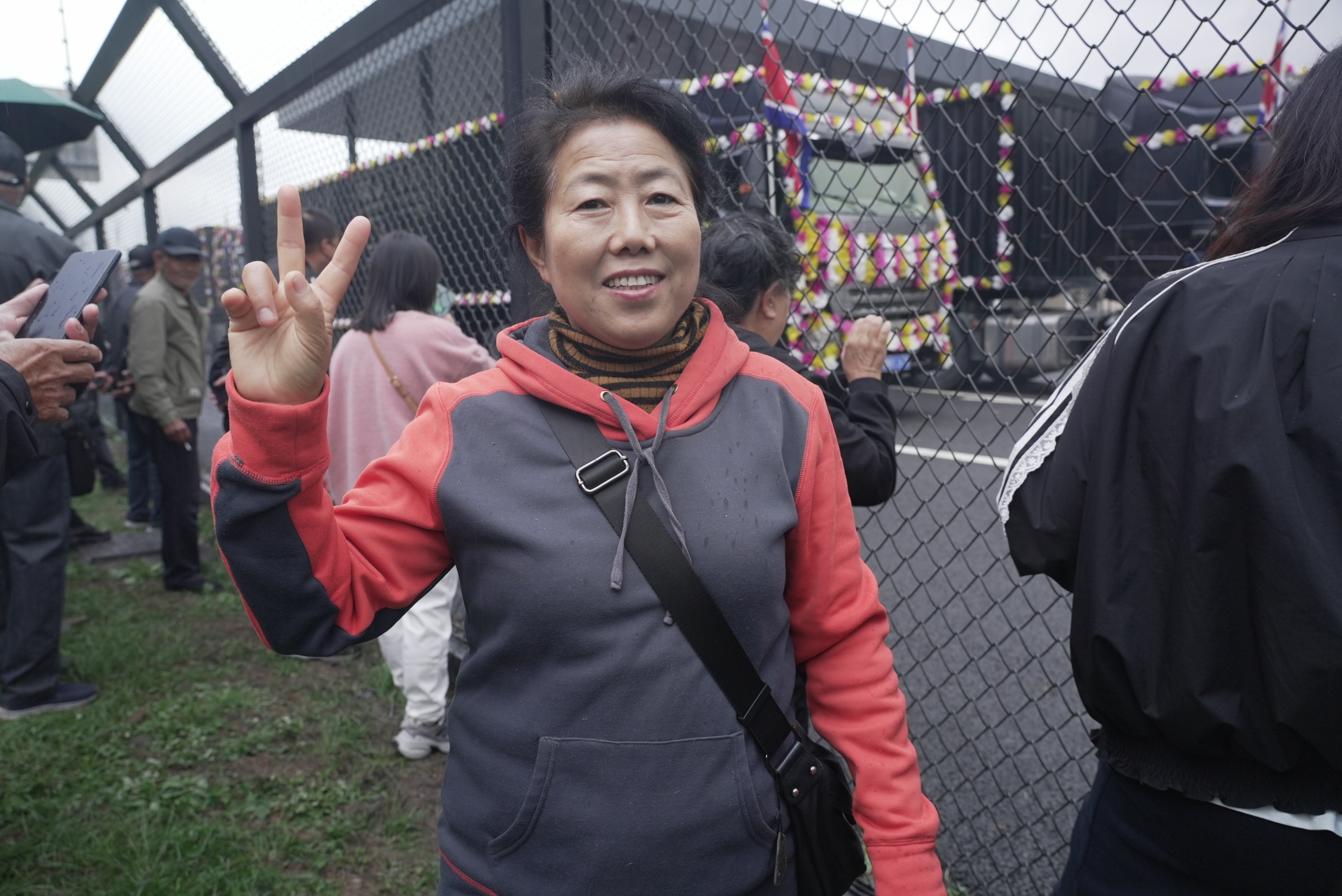 Ms Zhang makes a peace gesture as she stands among a crowd