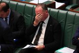 Barnaby Joyce covers his face while wiping his eyes with his right hand during question time.