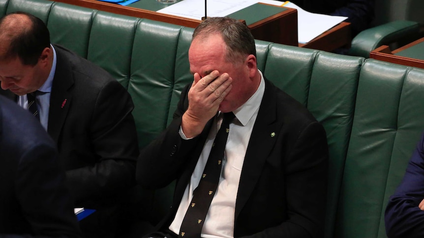 Barnaby Joyce covers his face while wiping his eyes with his right hand during question time.