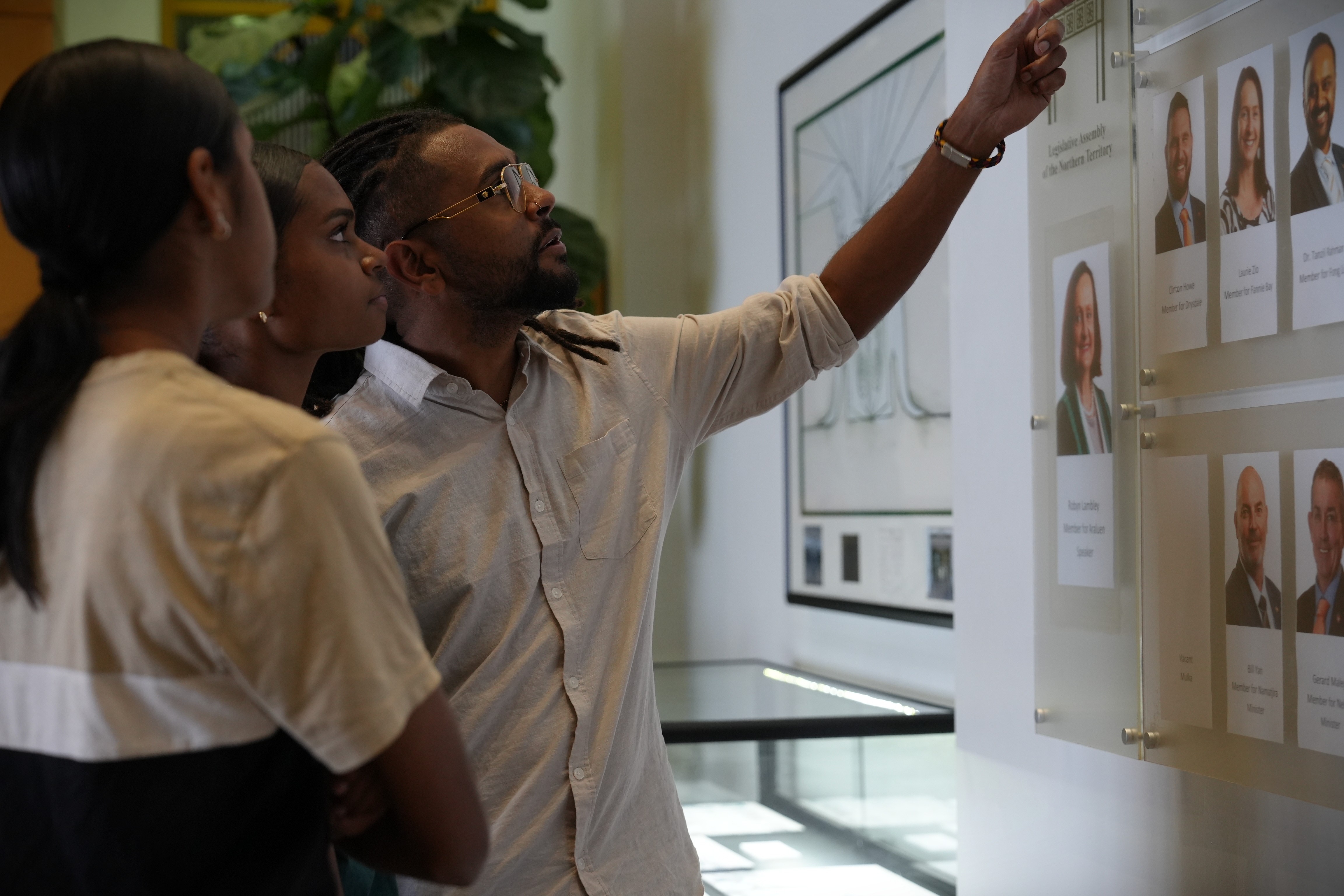 A man standing with his daughters and pointing at photos of politicians inside NT parliament.