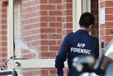 An Australian Federal Police forensic officer enters the main door of a building in Lakemba in Sydney, Tuesday, August 1, 2017.