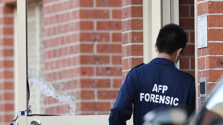 An Australian Federal Police forensic officer enters the main door of a building in Lakemba in Sydney, Tuesday, August 1, 2017.