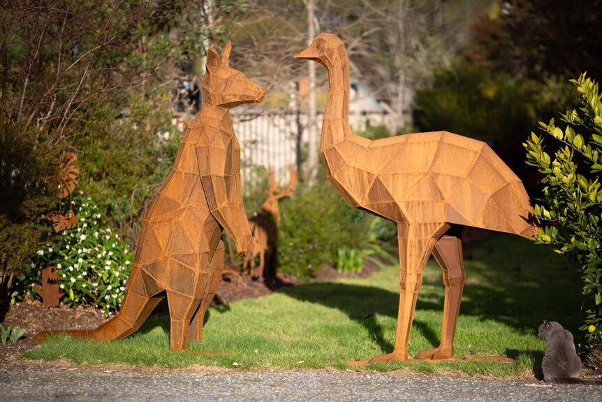 A rusted steel sculpture of a kangaroo facing a rusted steel sculpture of an emu
