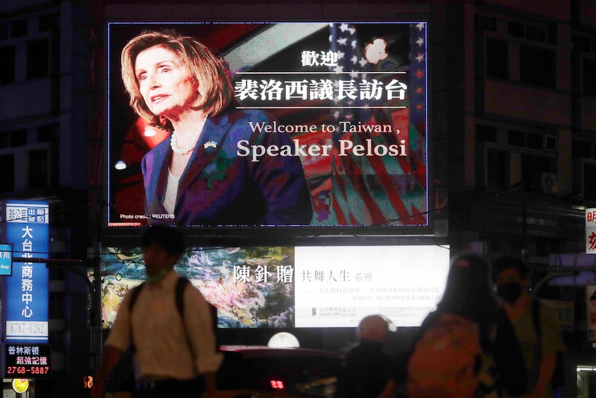 People walk past a billboard welcoming U.S. House Speaker Nancy Pelosi, in Taipei, Taiwan