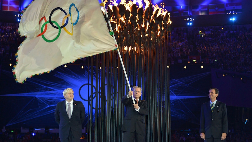 President of the International Olympic Committee Jacques Rogge holds the Olympic flag.