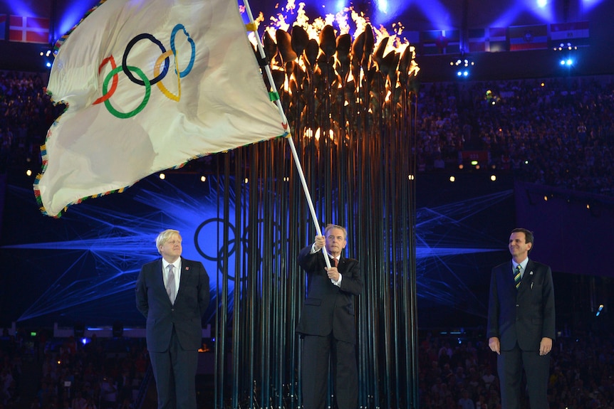 President of the International Olympic Committee Jacques Rogge holds the Olympic flag.