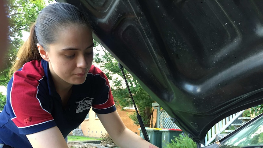 Iesha Te Paa works on a car engine in her front yard