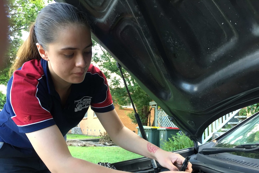 Iesha Te Paa works on a car engine in her front yard