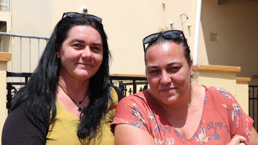 Two women, Janet Donnelly and Kara Welsh, stand close together in bright sunshine, smiling at the camera.