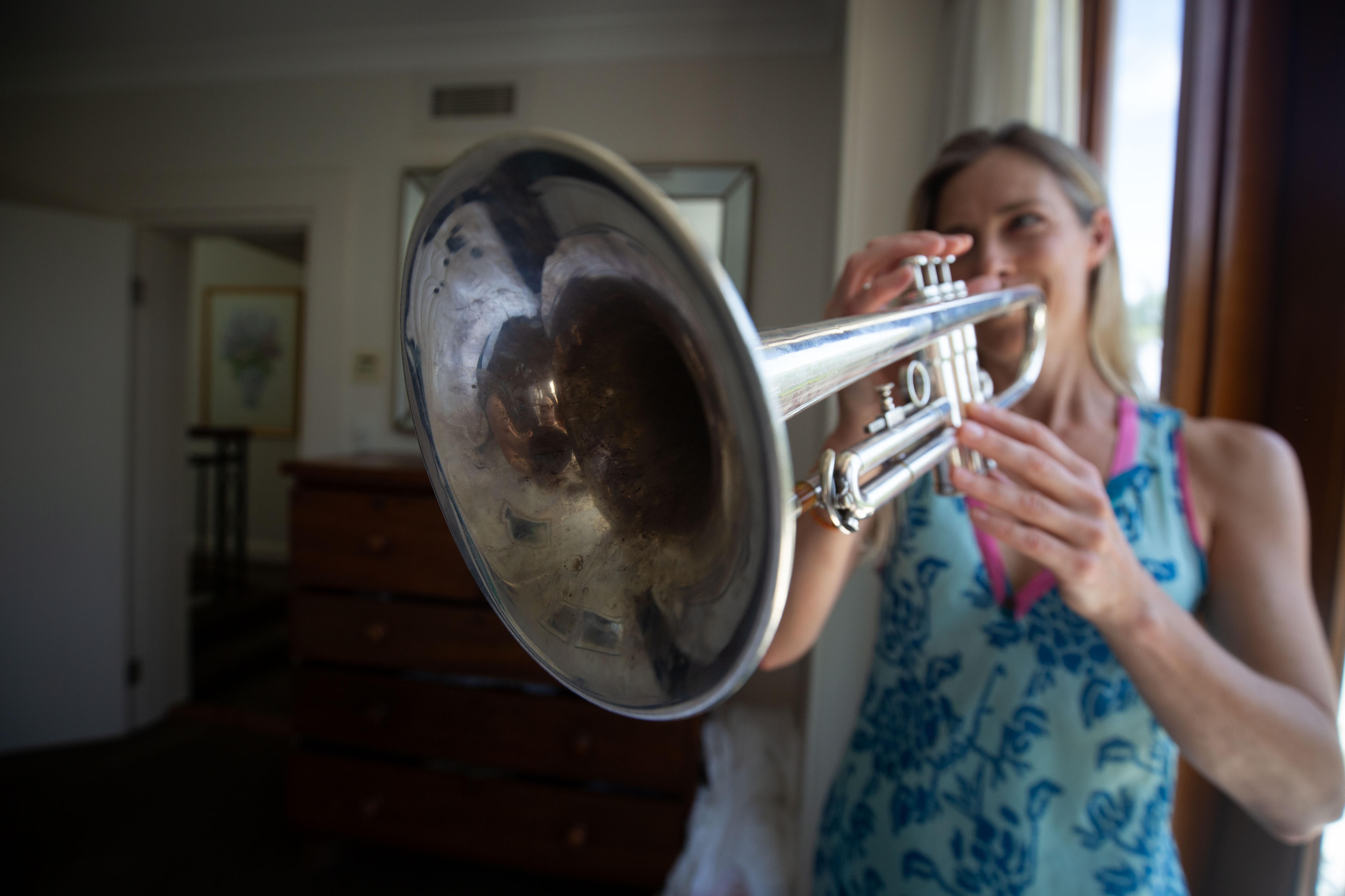 Belinda Pratten playing her trumpet, dressed in a bright blue top.
