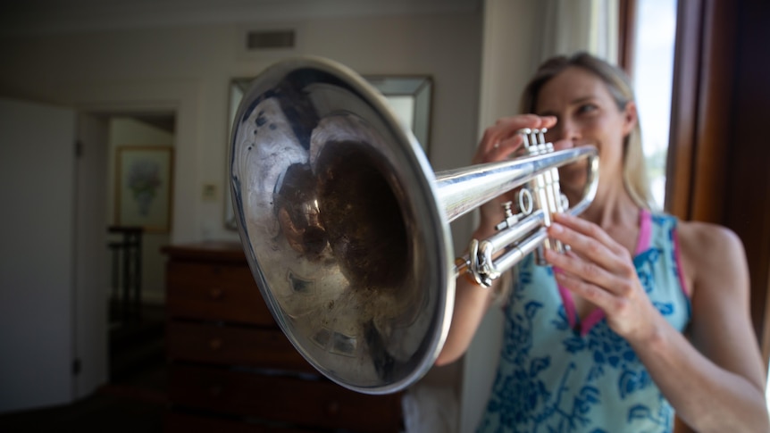Belinda Pratten playing her trumpet, dressed in a bright blue top.